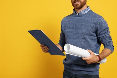 Professional engineer with clipboard and draft on yellow background, closeup