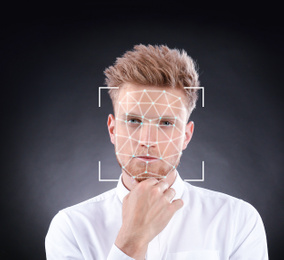 Image of Facial recognition system. Young man with scanner frame and digital biometric grid on dark background
