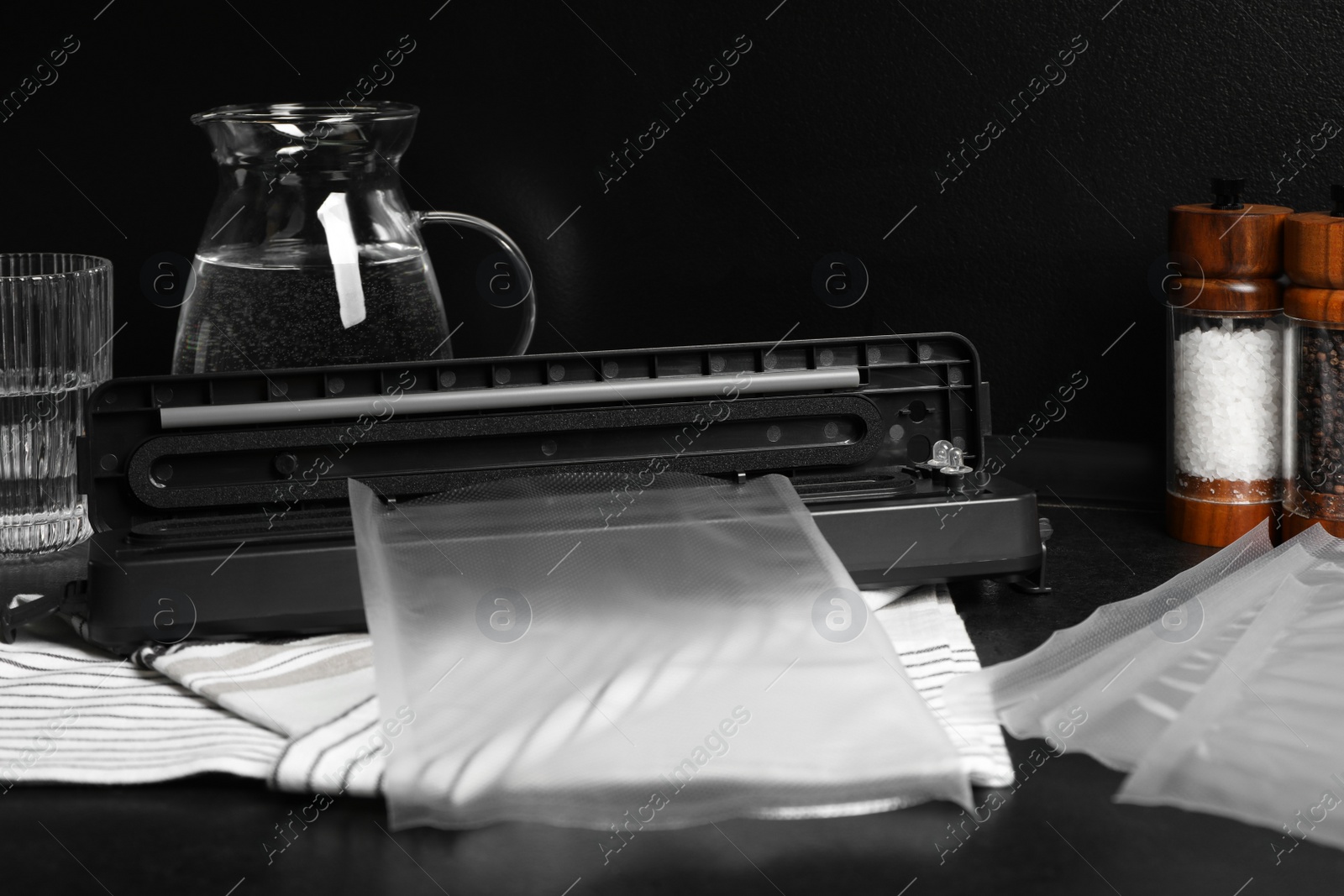 Photo of Sealer for vacuum packing with plastic bags on black kitchen countertop
