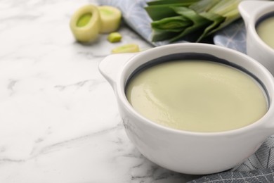 Photo of Tasty leek soup on white marble table, closeup with space for text