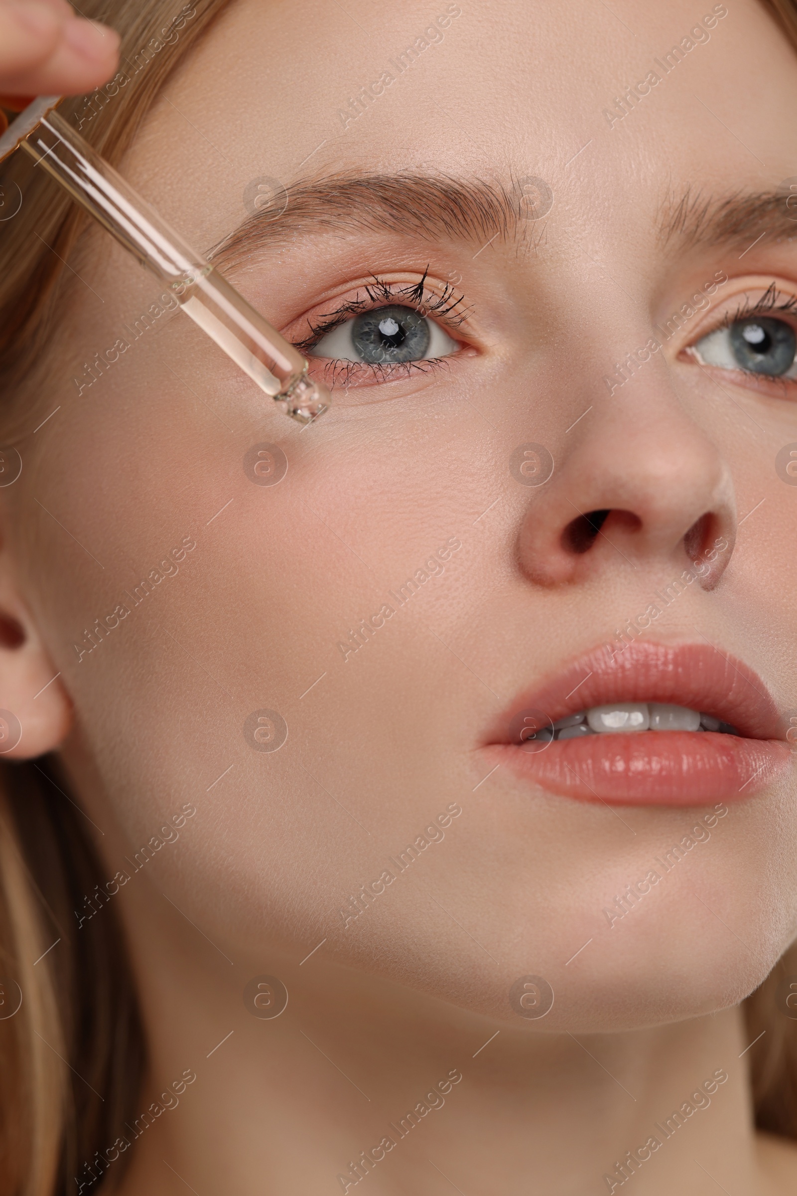 Photo of Woman applying essential oil onto face, closeup