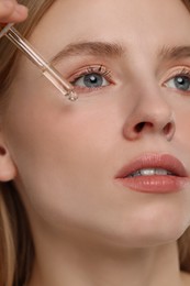 Woman applying essential oil onto face, closeup