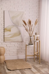 Photo of Fluffy reed plumes and painting in stylish room interior