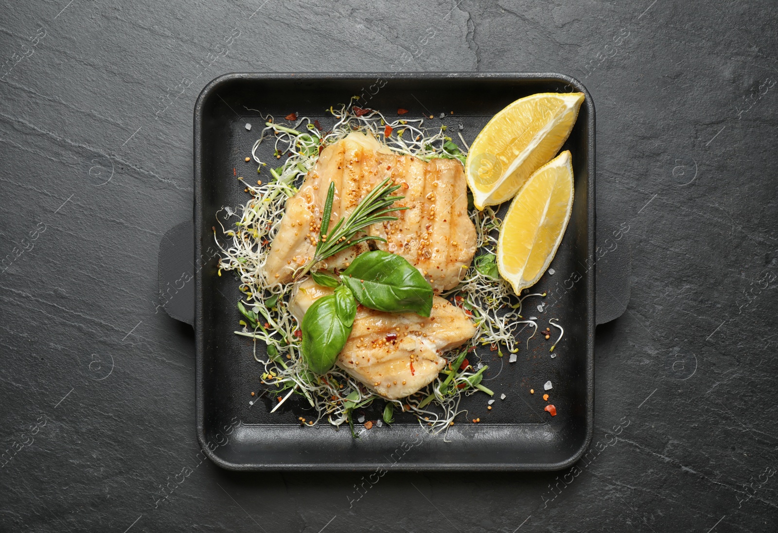 Photo of Tasty grilled fish on black table, top view