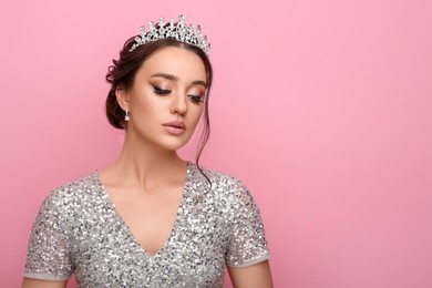 Beautiful young woman wearing luxurious tiara on pink background, space for text