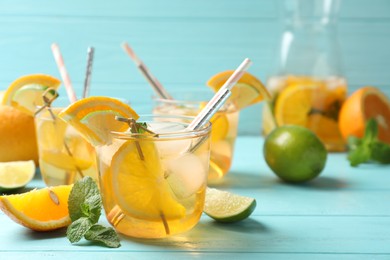 Delicious refreshing drink with orange and lime slices on light blue wooden table