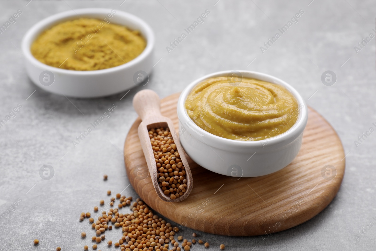 Photo of Delicious mustard and seeds on light grey table