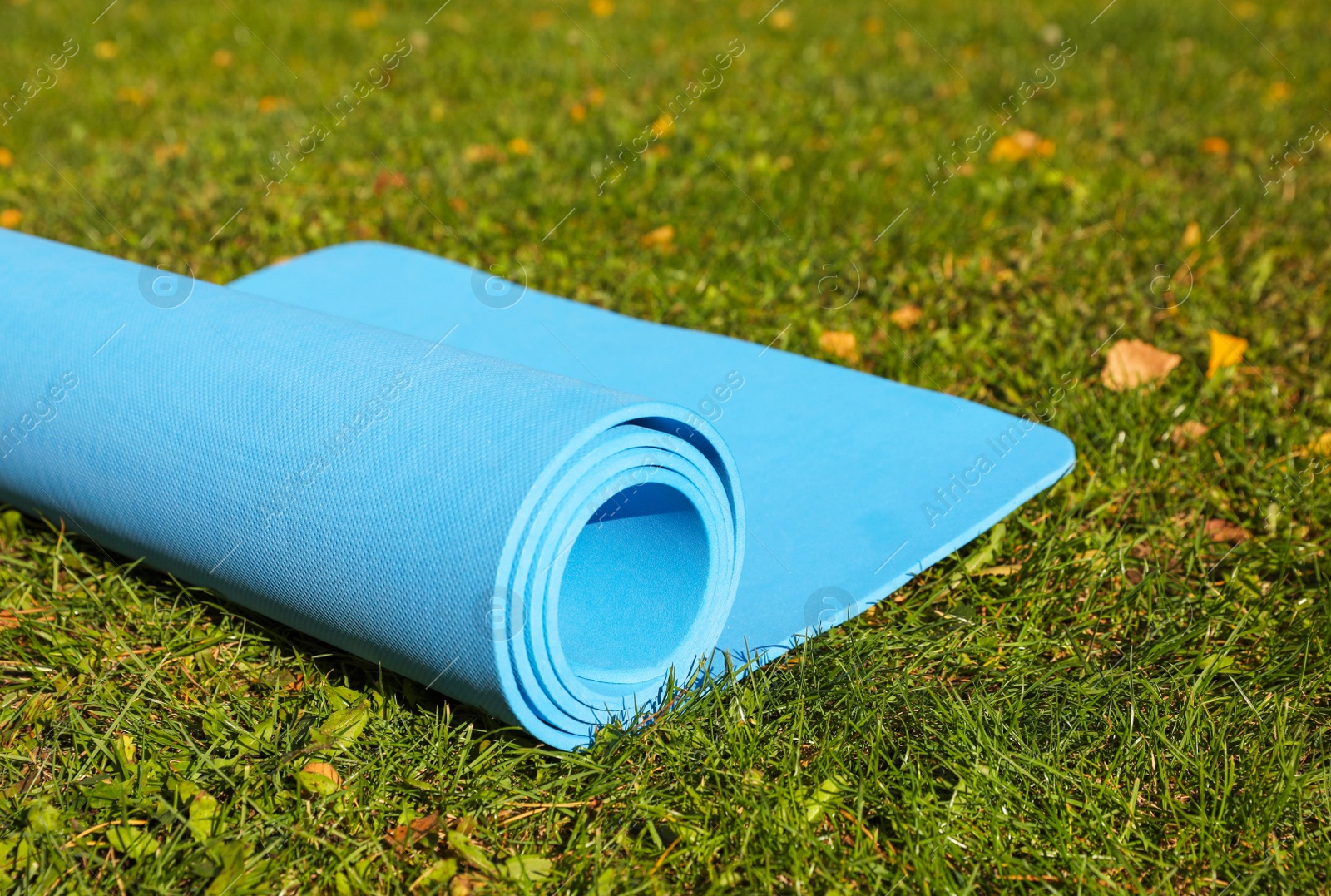 Photo of Blue karemat or fitness mat on fresh green grass outdoors, closeup