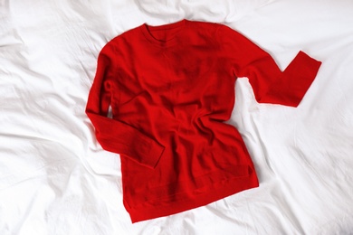 Red cashmere sweater on white fabric, top view