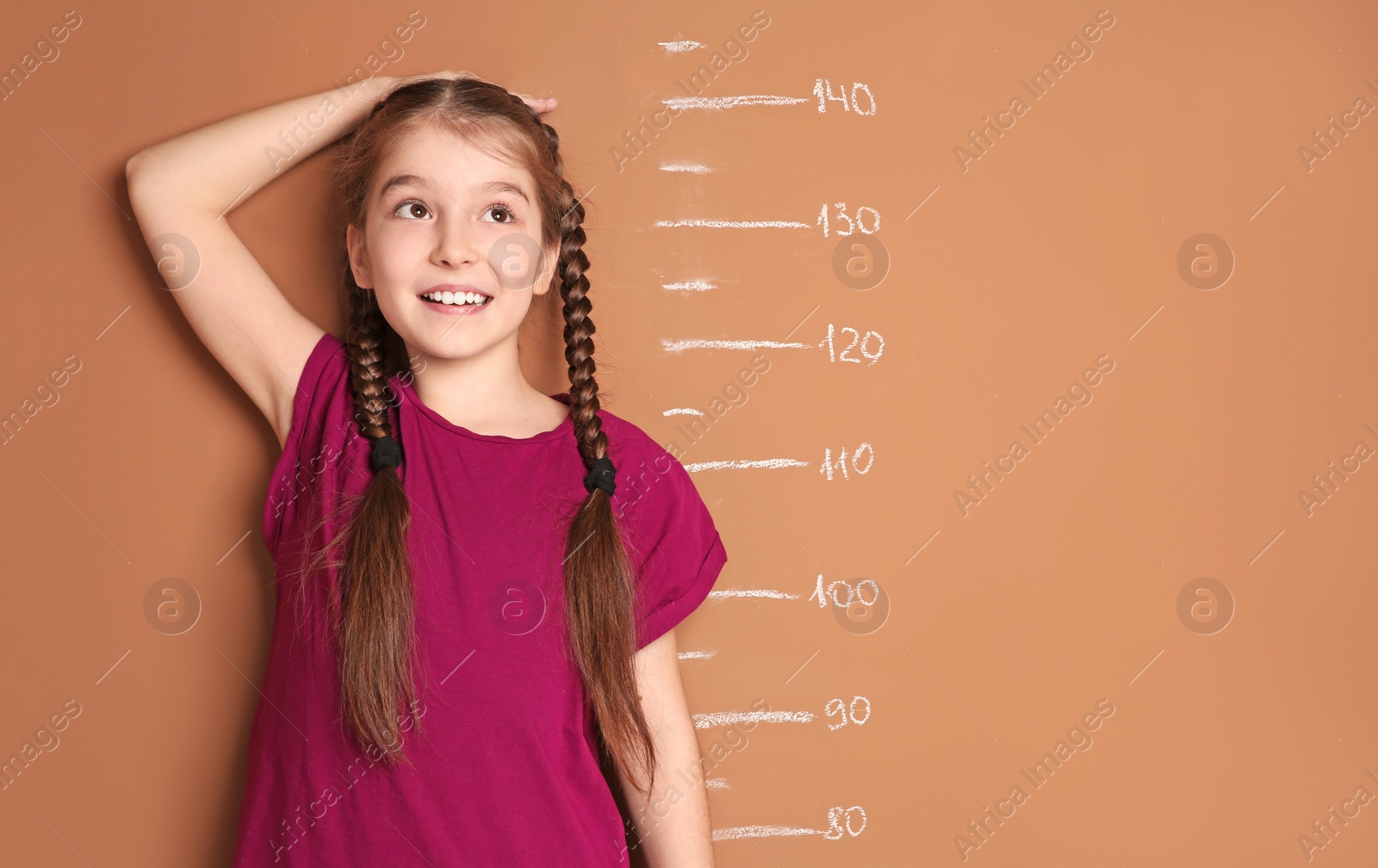 Photo of Little girl measuring her height on color background