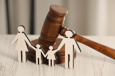 Photo of Law concept. Gavel and figures of parents with children on white wooden table, closeup