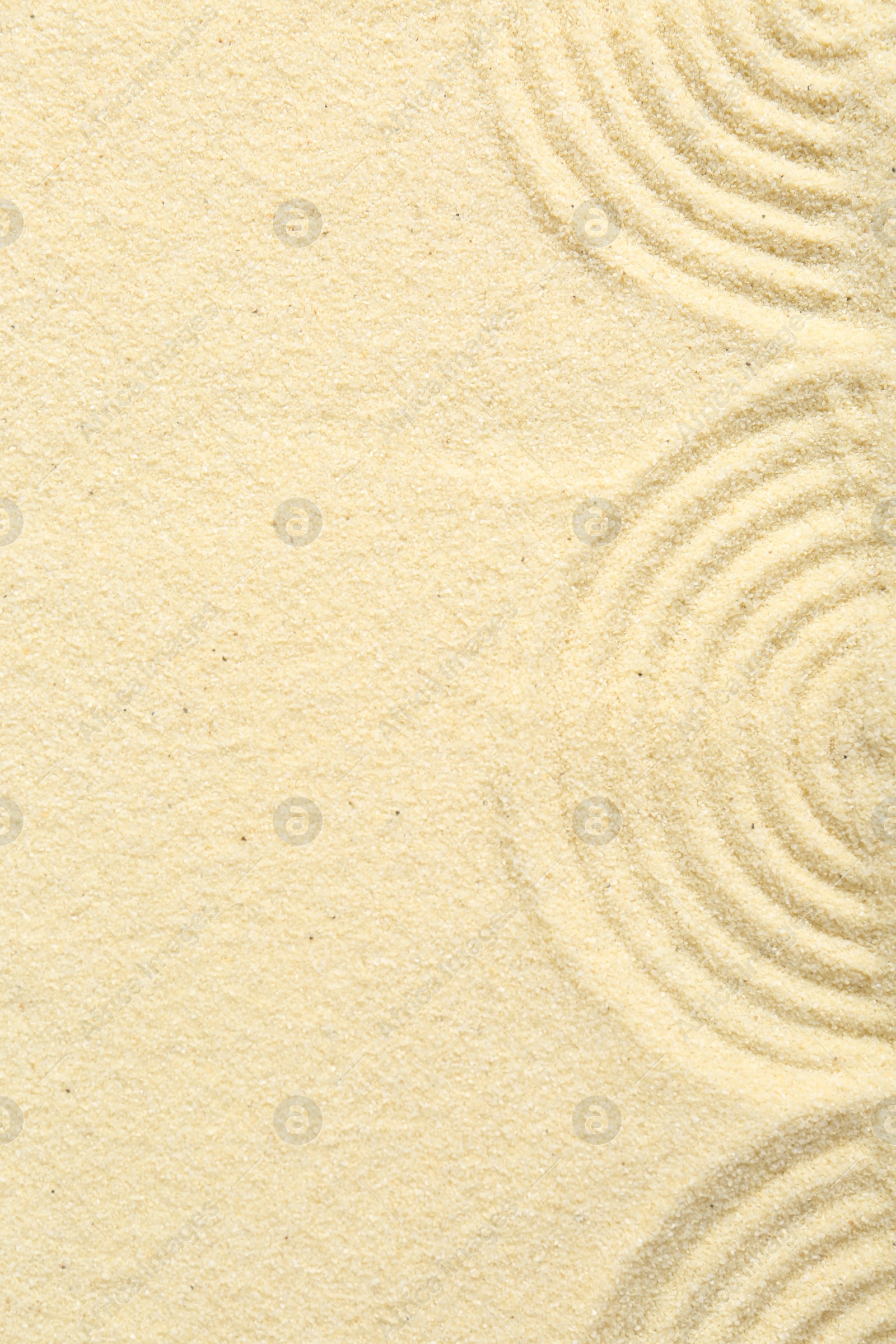 Photo of Zen rock garden. Wave pattern on beige sand, top view