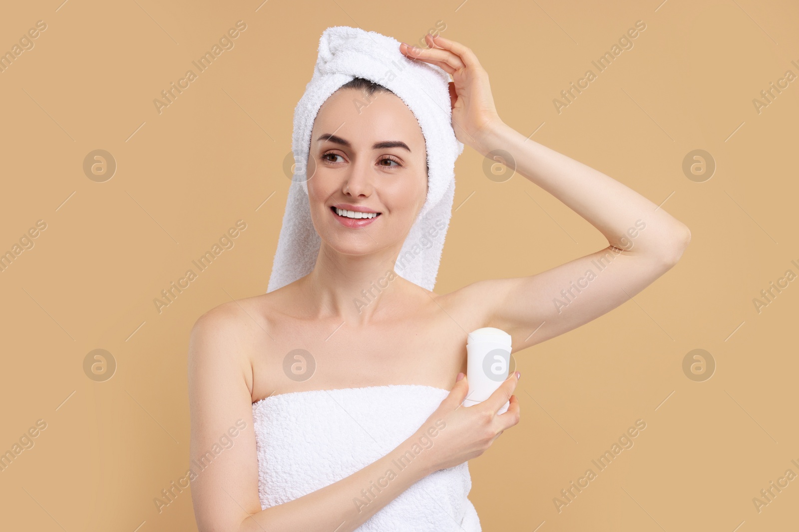 Photo of Beautiful woman applying deodorant on beige background