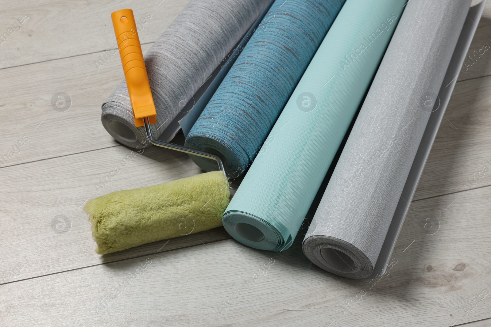 Photo of Different wallpaper rolls and roller on floor