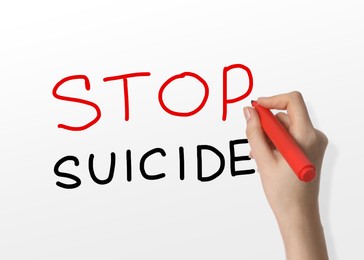 Image of Woman writing phrase Stop Suicide on whiteboard, closeup