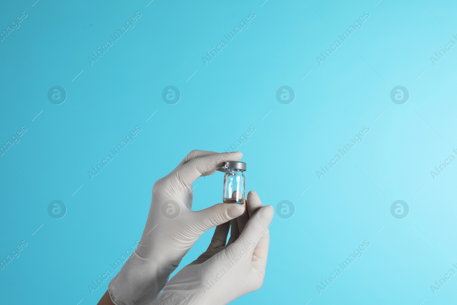 Photo of Female doctor holding glass vial on color background, closeup view with space for text. Medical object