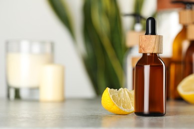 Photo of Bottle of #essential oil and lemon on light grey table, space for text