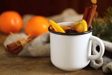 Photo of Mug with aromatic mulled wine on wooden table