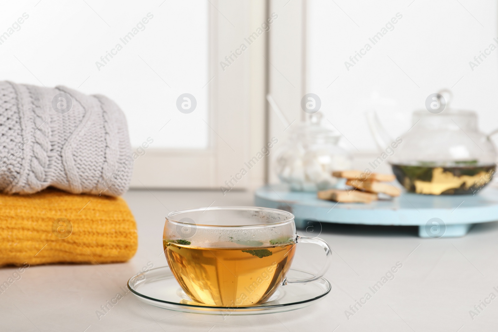 Photo of Cup of fresh tea on windowsill indoors. Winter drink