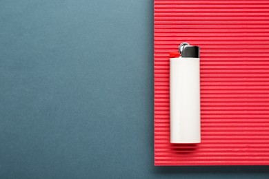 Photo of Stylish small pocket lighter with red corrugated fiberboard on black background, top view. Space for text