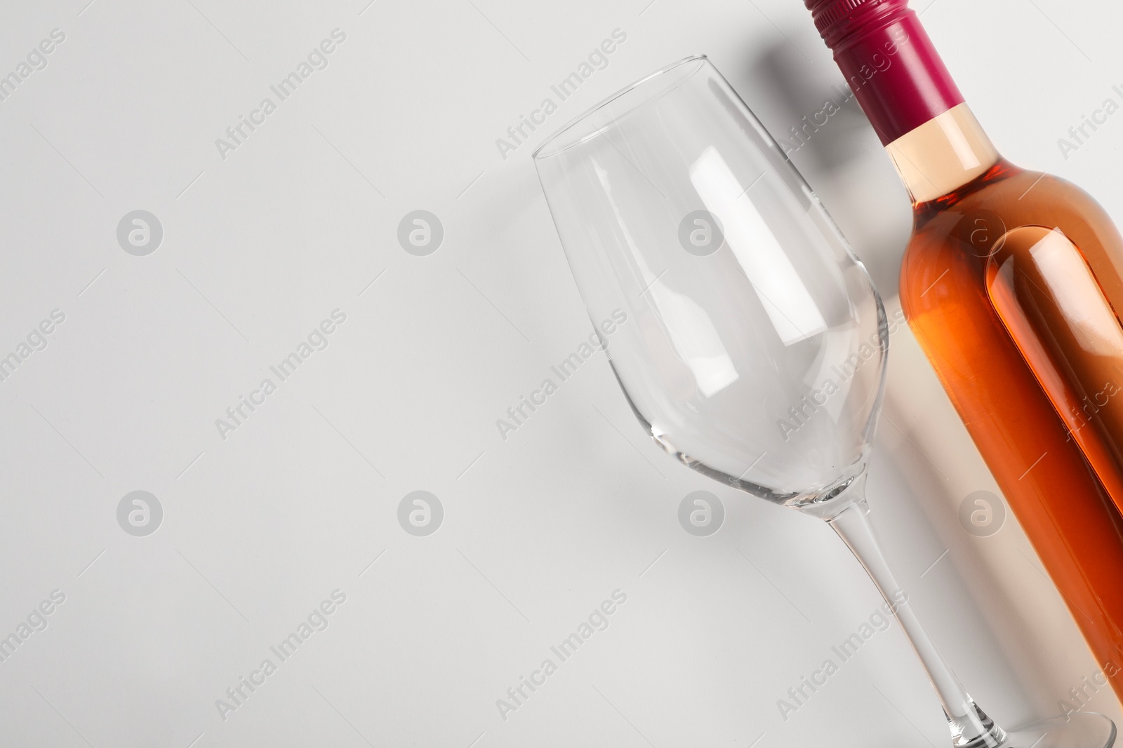 Photo of Bottle of expensive rose wine and wineglass on white background, top view. Space for text