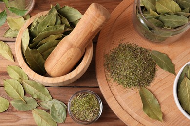 Photo of Whole and ground aromatic bay leaves on wooden table, above view