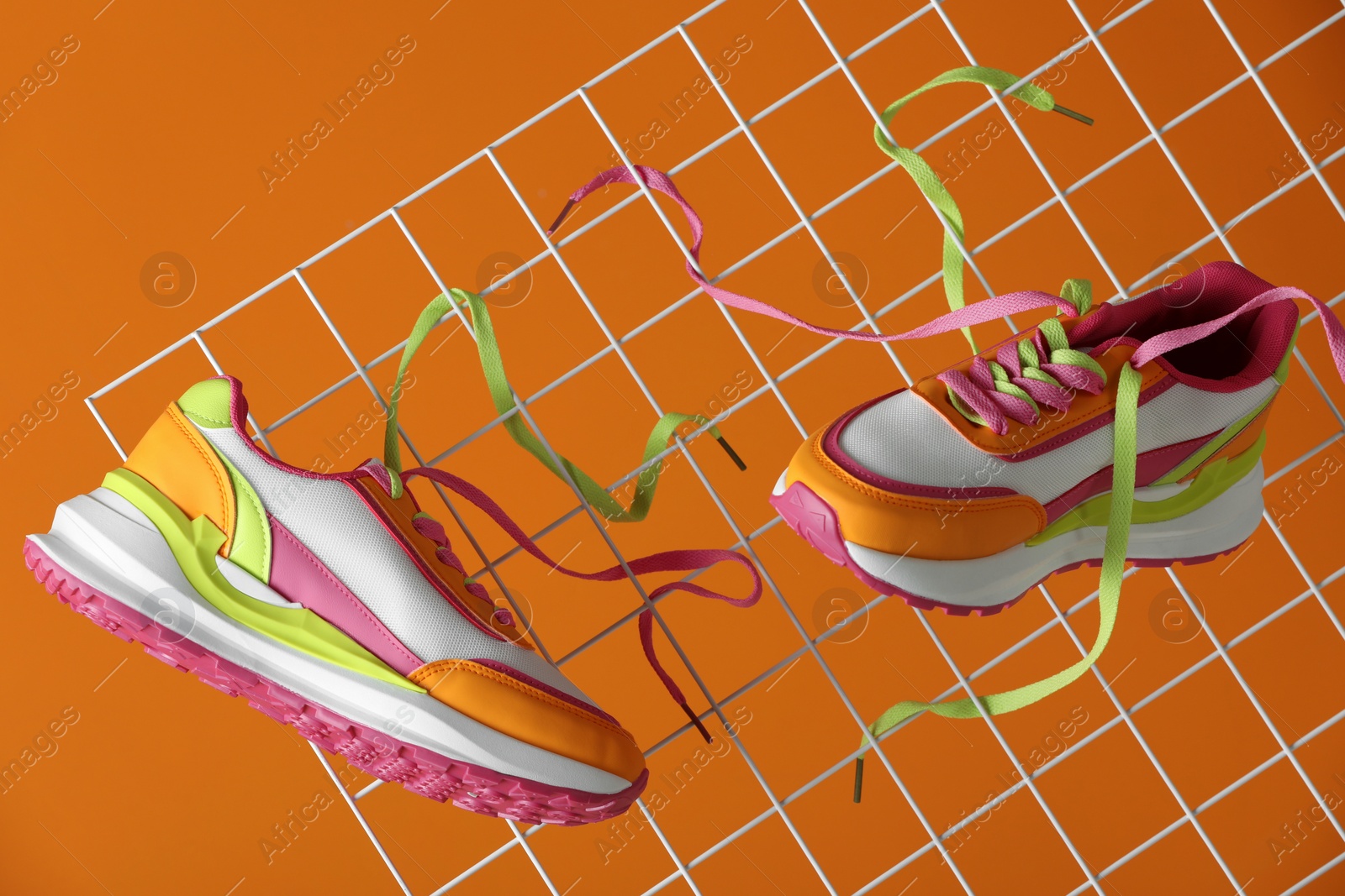 Photo of Stylish presentation of trendy sneakers on orange background