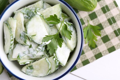 Delicious cucumber salad in bowl on white table, flat lay. Space for text