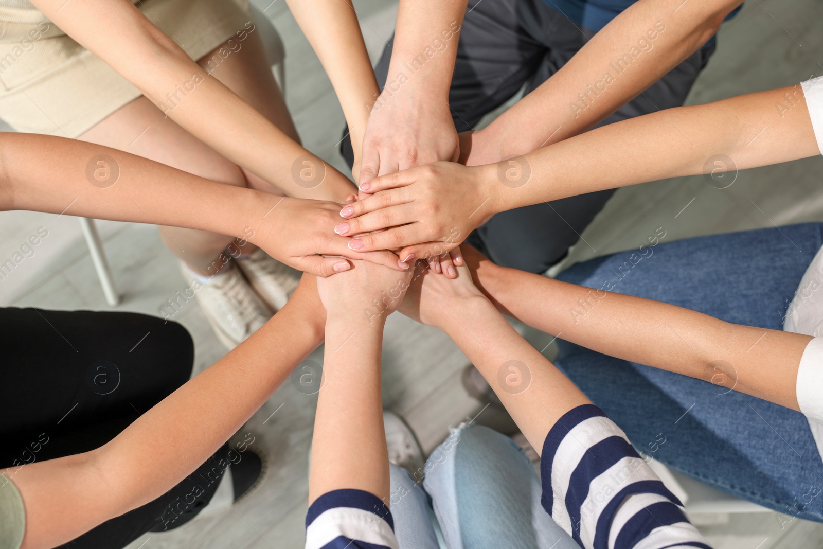 Photo of Group of people holding hands together indoors, above view. Unity concept