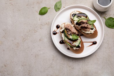 Photo of Delicious bruschettas with balsamic vinegar and toppings on light textured table, flat lay. Space for text