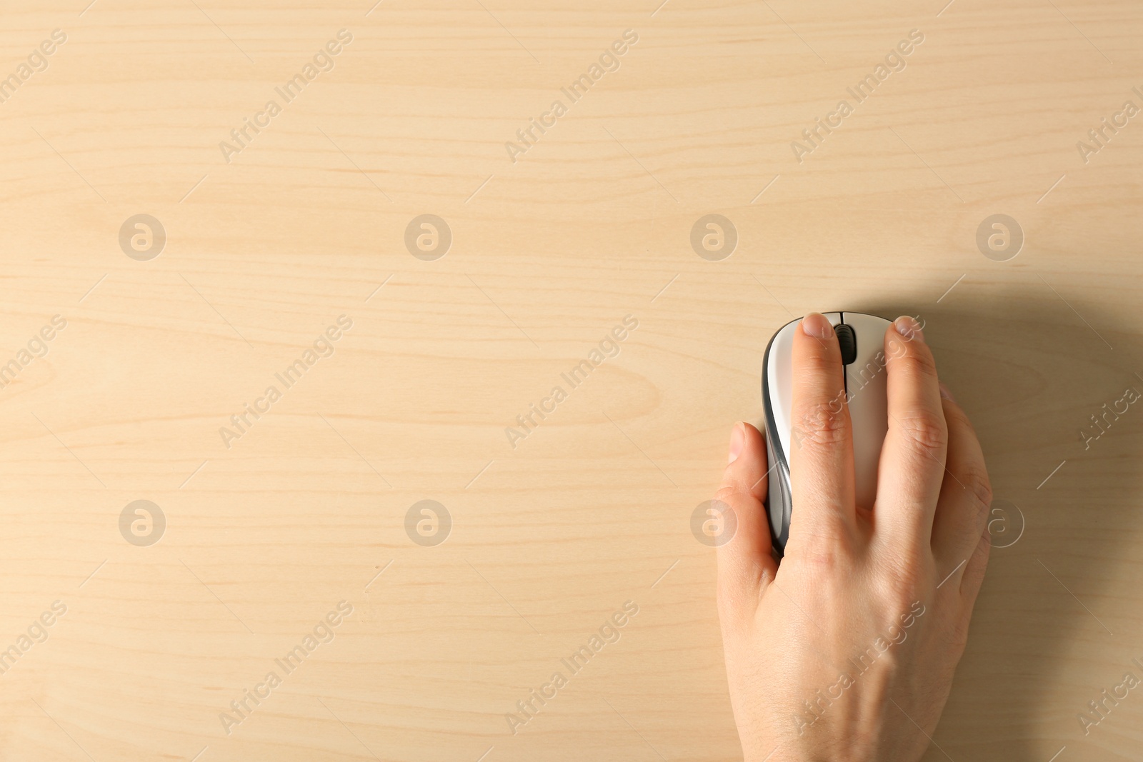 Photo of Woman using computer mouse on wooden background, top view. Space for text