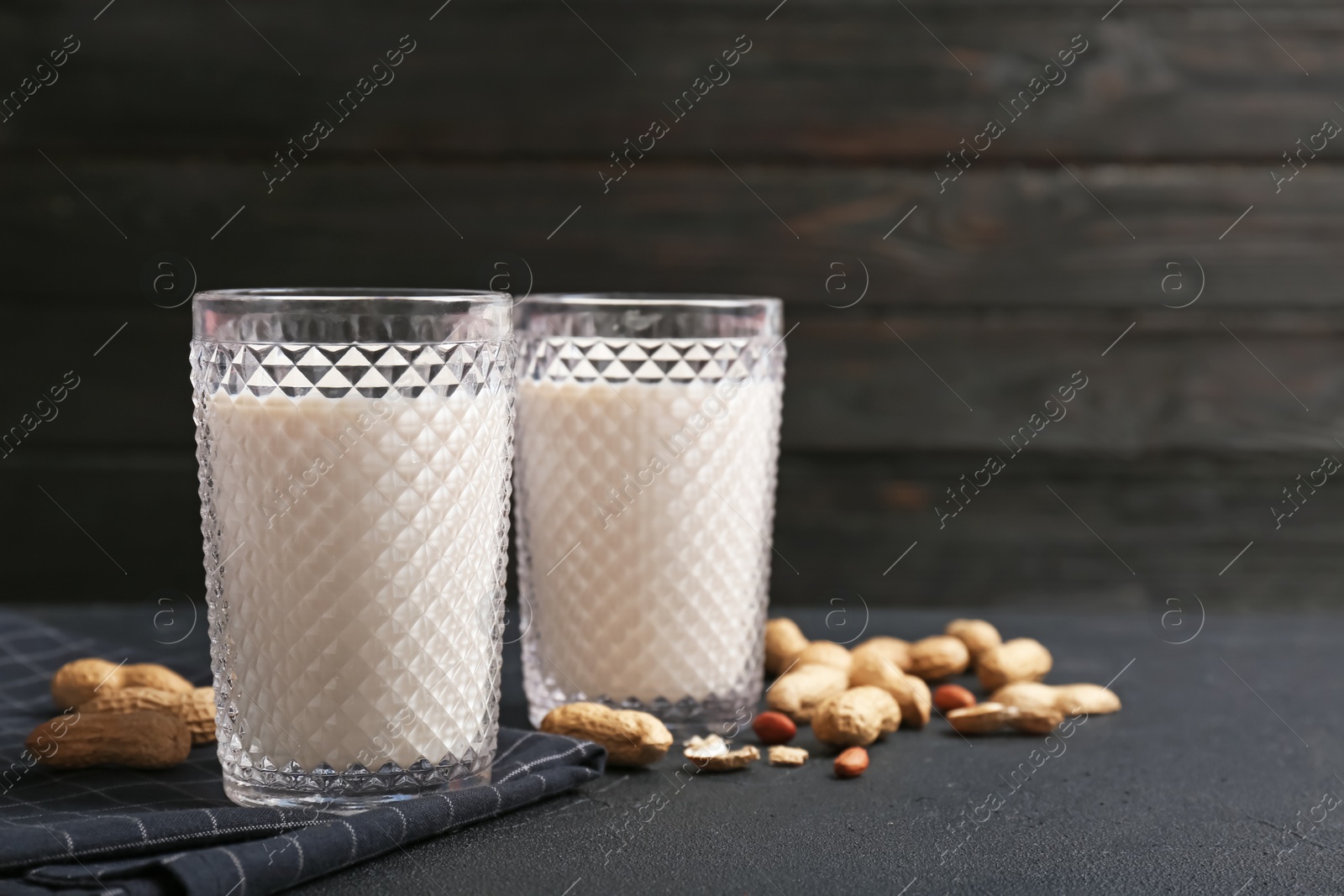 Photo of Glasses with peanut milk and nuts on grey table