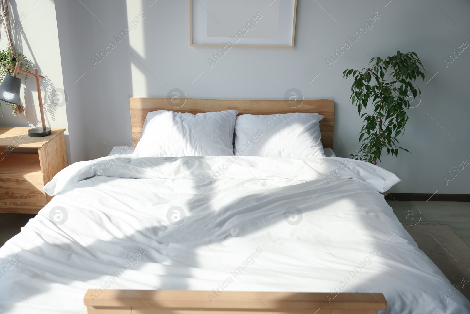 Photo of Large comfortable bed with soft pillows and blanket indoors