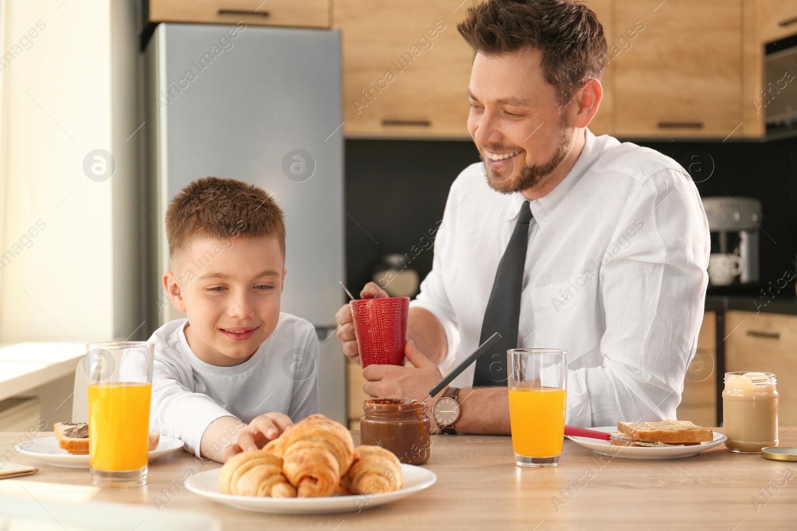 Photo of Dad and son having breakfast together in kitchen