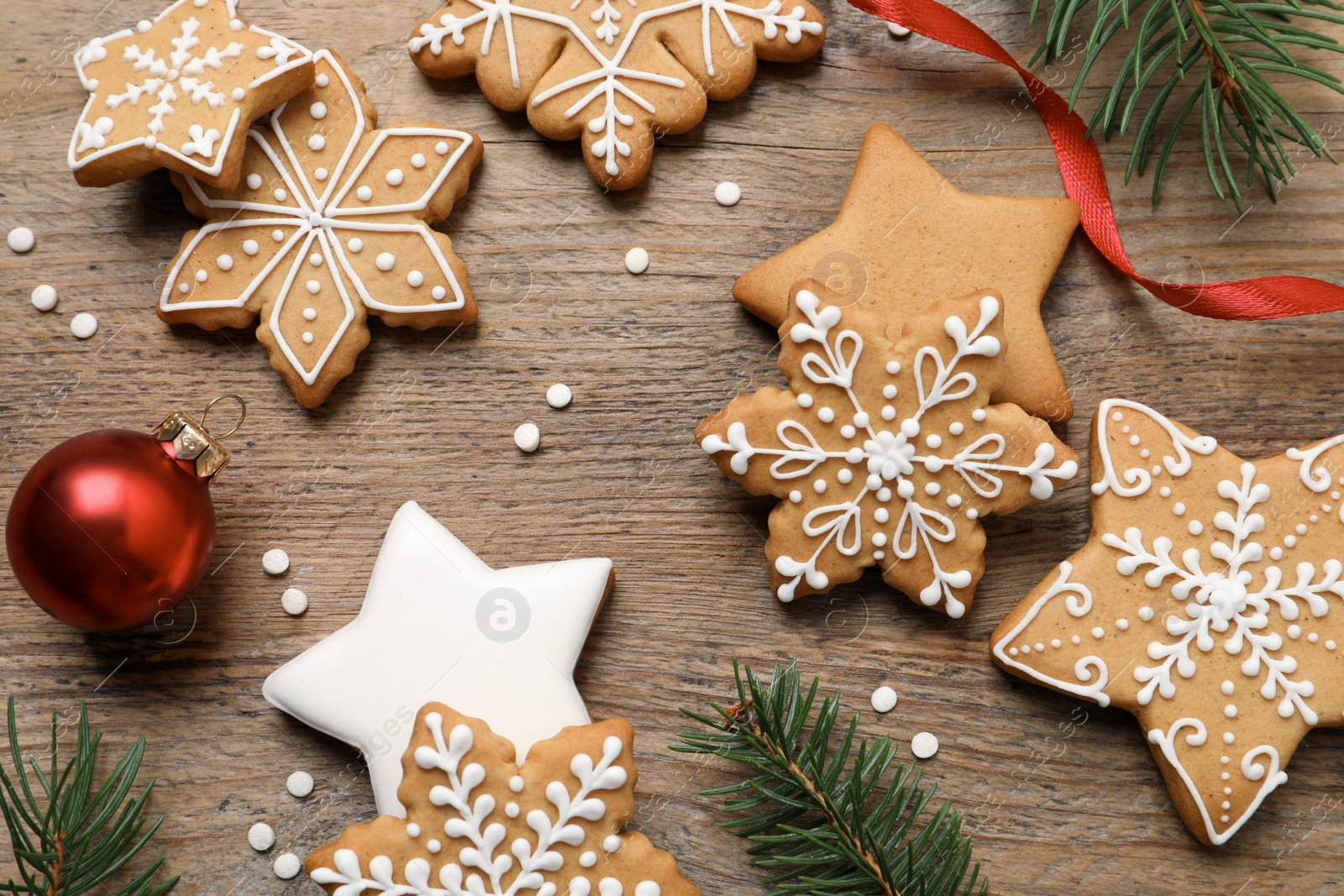 Photo of Tasty Christmas cookies and festive decor on wooden table, flat lay