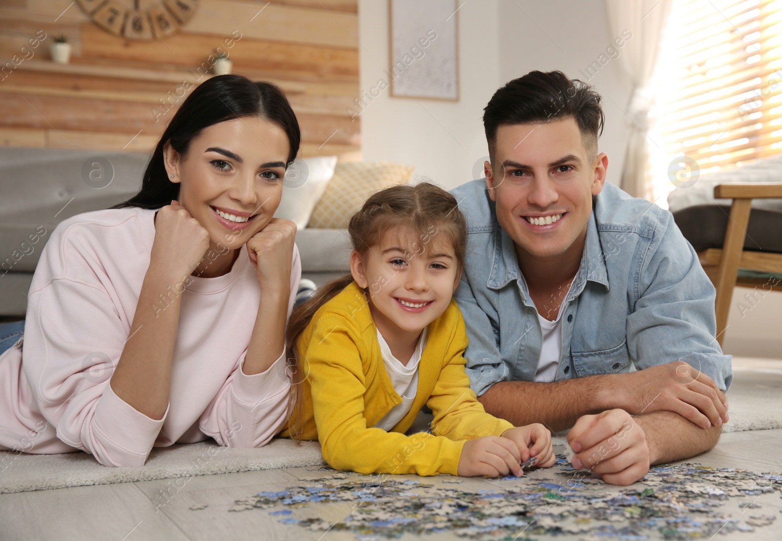 Photo of Happy family playing with puzzles on floor at home