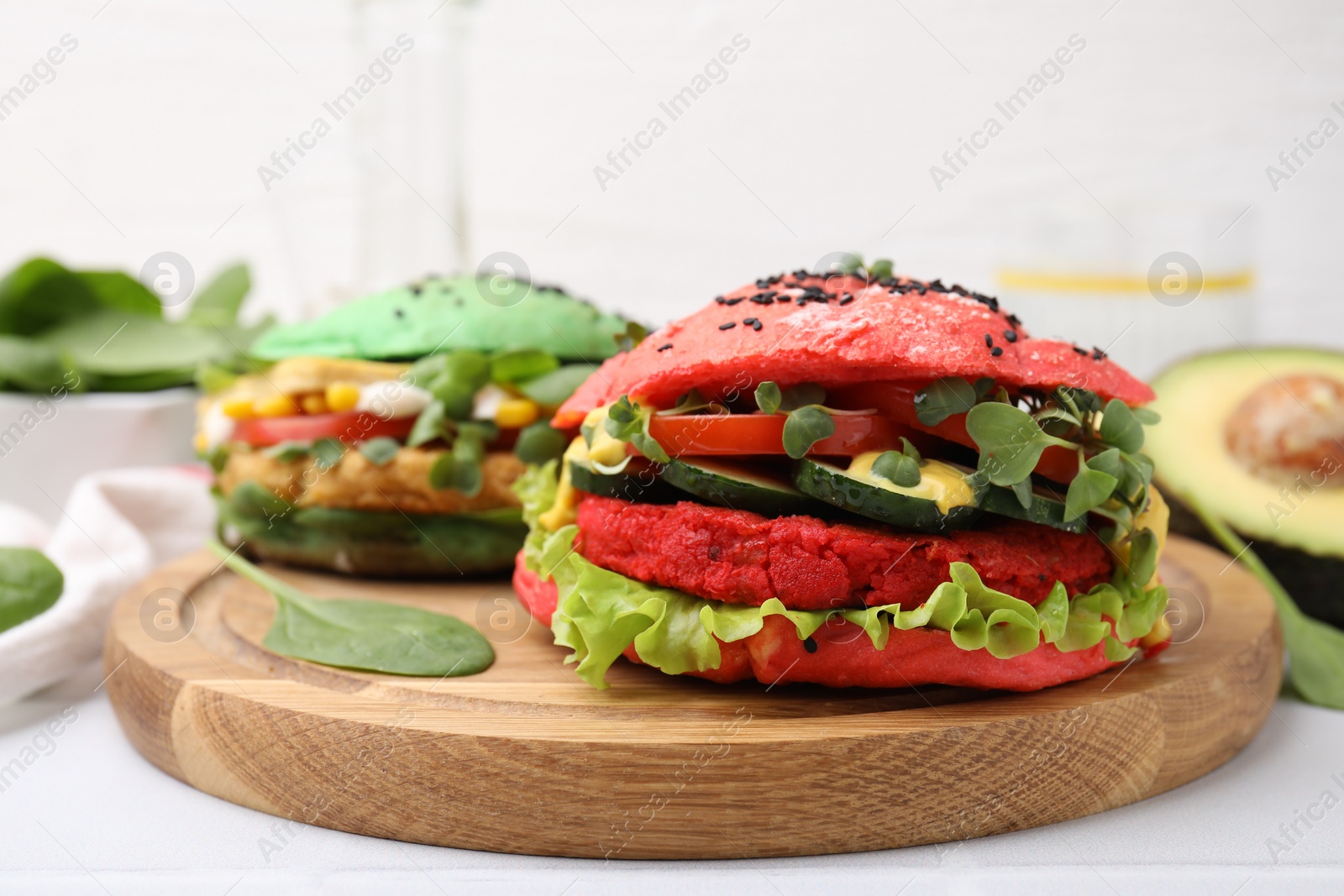 Photo of Tasty pink vegan burger with vegetables, patty and microgreens on white tiled table, closeup. Space for text