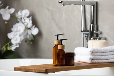 Photo of Personal care products and folded towels on bath tray indoors