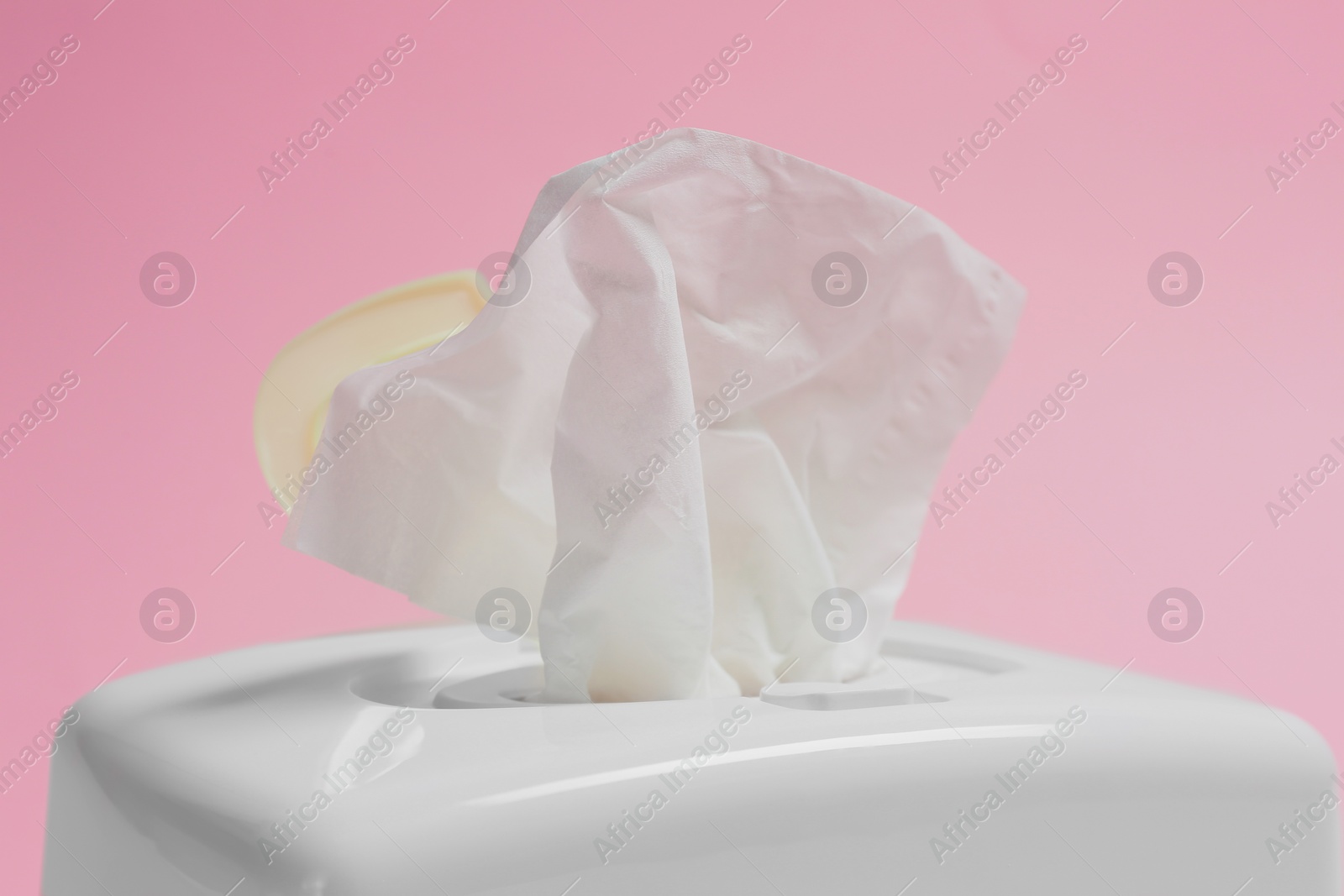 Photo of Holder with paper tissues on pink background, closeup