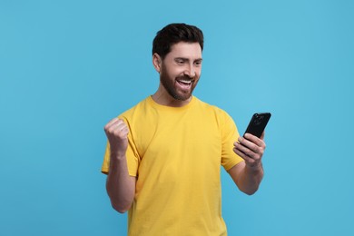 Photo of Happy man using smartphone on light blue background