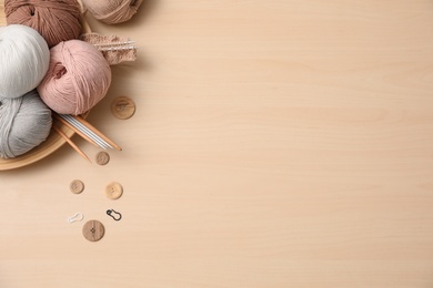 Flat lay composition with threads and crafting accessories on wooden table, space for text. Engaging hobby