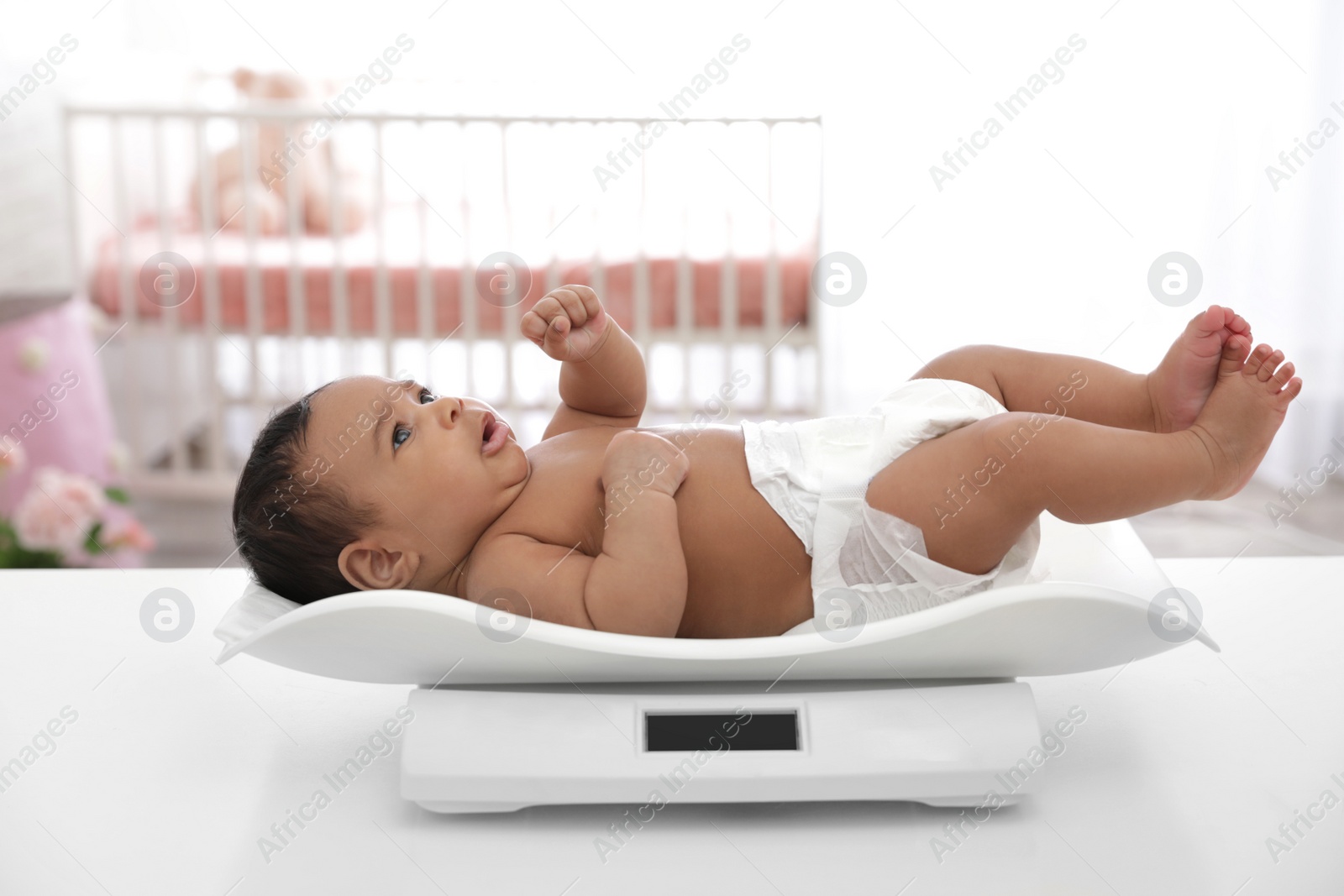 Photo of African-American baby lying on scales in light room