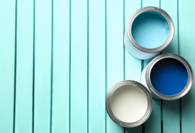 Colorful paint cans on blue wooden background, top view. Space for text