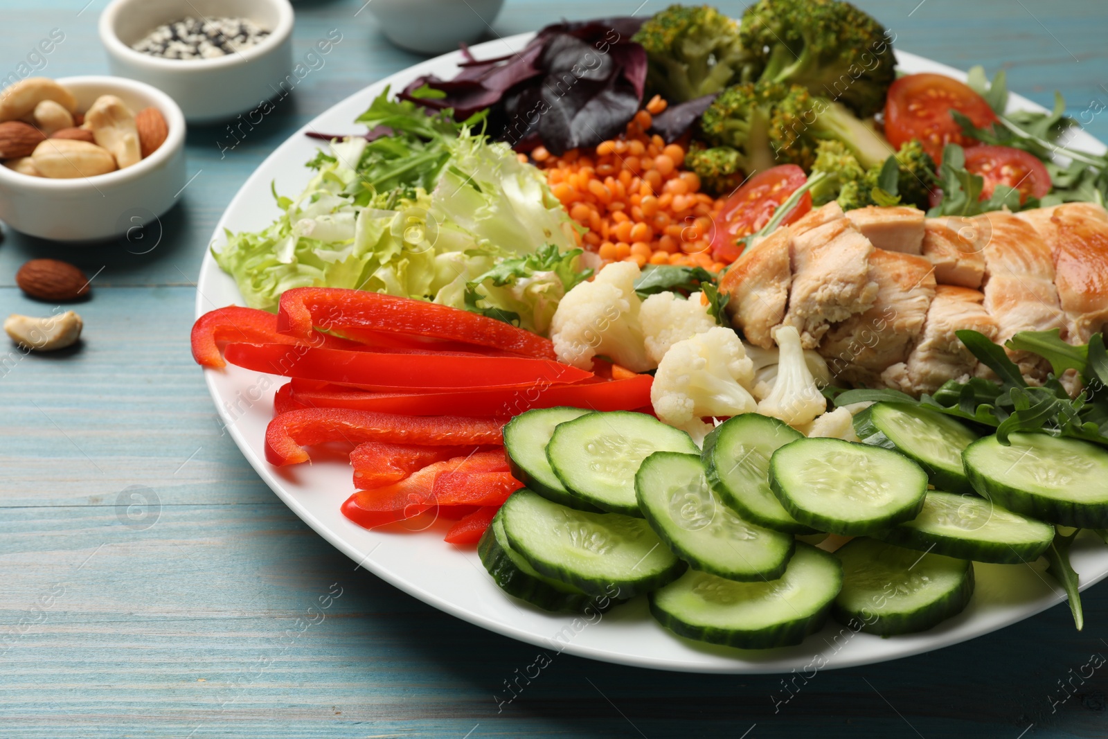 Photo of Balanced diet and healthy foods. Plate with different delicious products on light blue wooden table, closeup