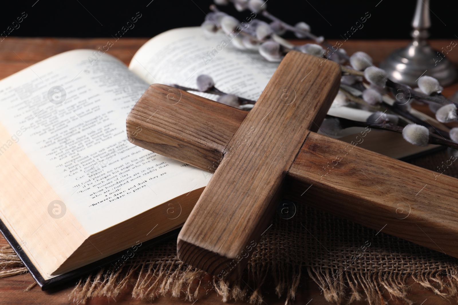 Photo of Cross, Bible and willow branches on wooden table, closeup