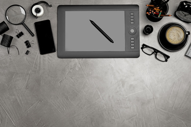 Photo of Flat lay composition with graphic drawing tablet and different office items on grey stone background, space for text. Designer's workplace