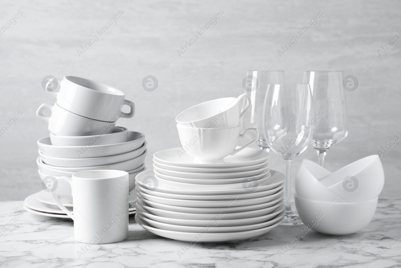 Photo of Set of clean dishware on marble table