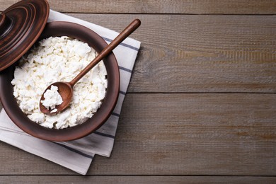 Photo of Top view of clay pot with cottage cheese and spoon on grey wooden table, space for text