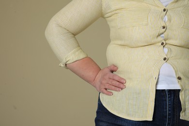 Photo of Overweight woman in tight shirt on beige background, closeup