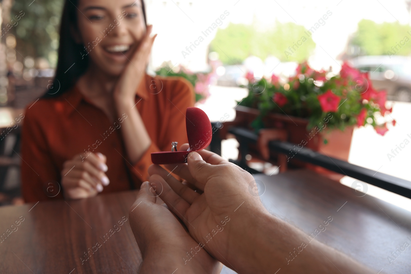 Photo of Man with engagement ring making proposal to his girlfriend in outdoor cafe, focus on hands